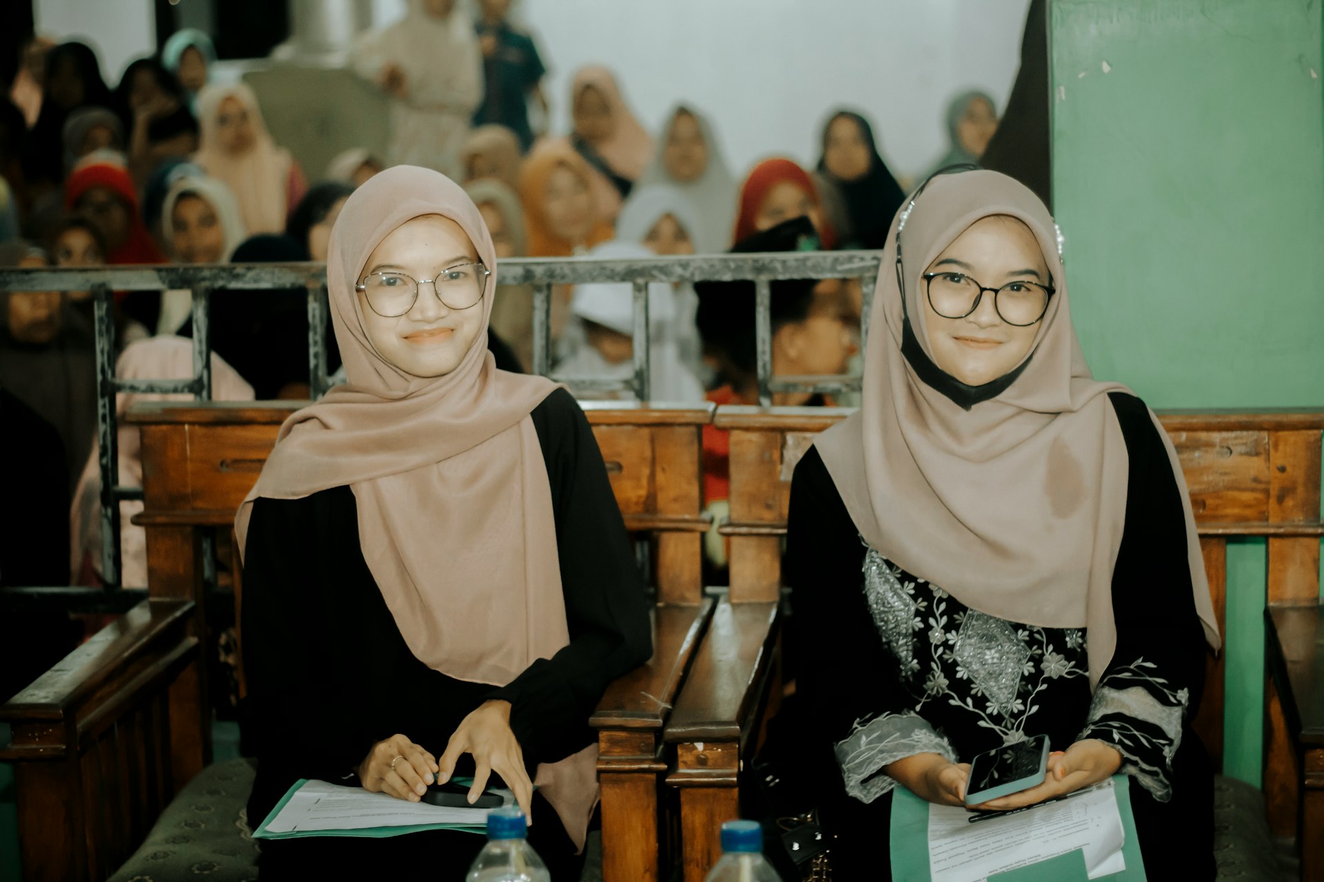 Two women sitting next to each other in front of a crowd